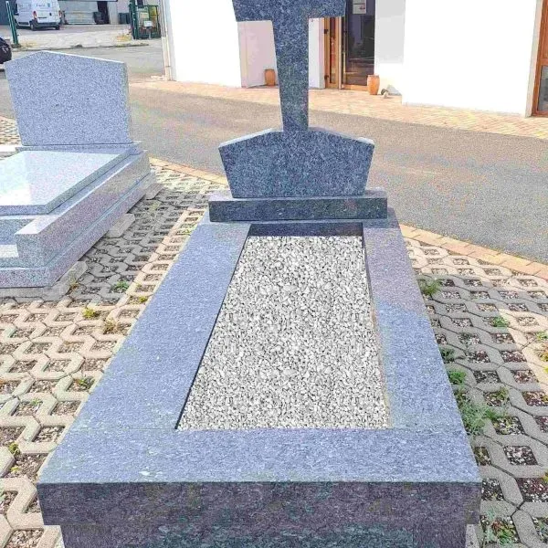 Monument funéraire en granit gris foncé avec stèle surmontée d'une croix et tombale à graviers