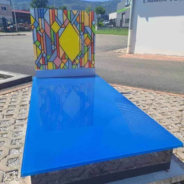 Tombe moderne en verre bleu vif avec stèle au motif de vitrail multicolore