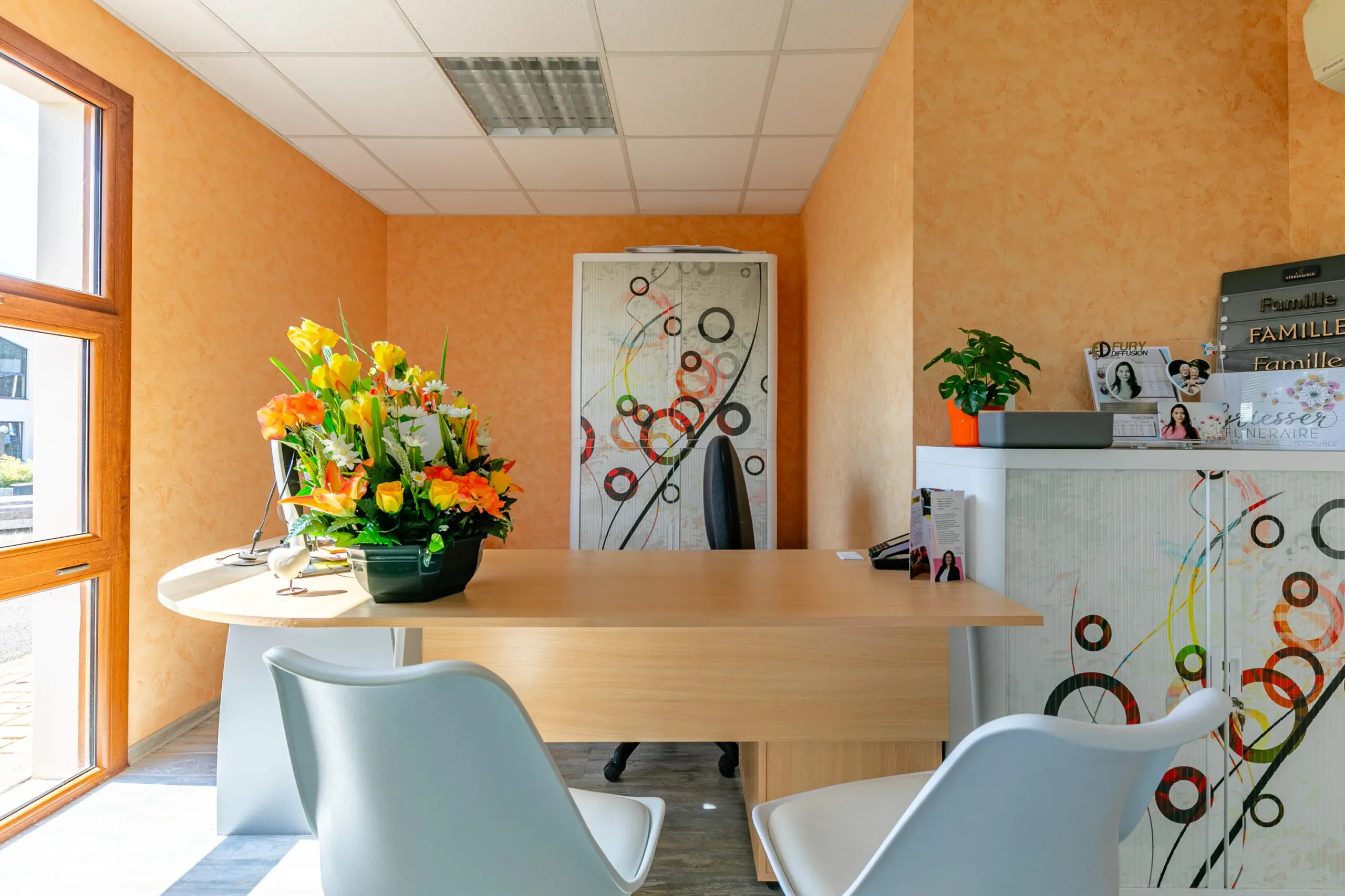 Bureau d'accueil lumineux des pompes funèbres avec fleurs colorées et sièges pour les visiteurs