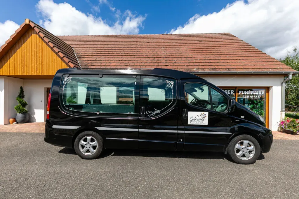 Vue de profil du véhicule corbillard noir stationné devant l'agence Griesser Funéraire