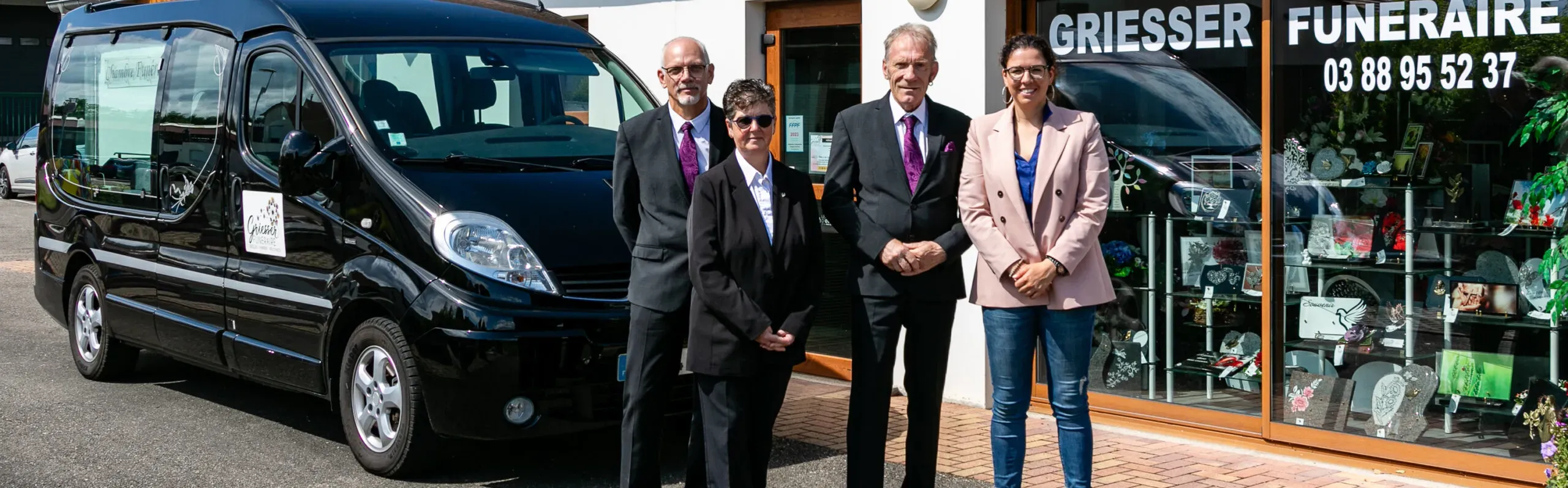 L'équipe Griesser Funéraire pose devant l'agence et le corbillard