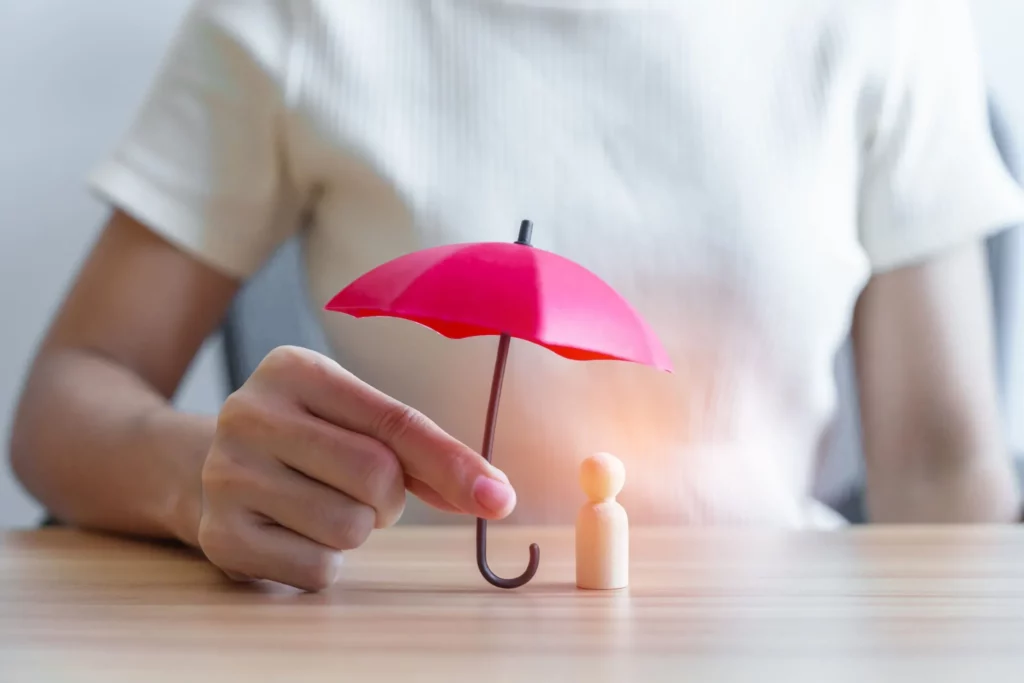 Allégorie de la protection : une main abrite un personnage sous un parapluie rouge